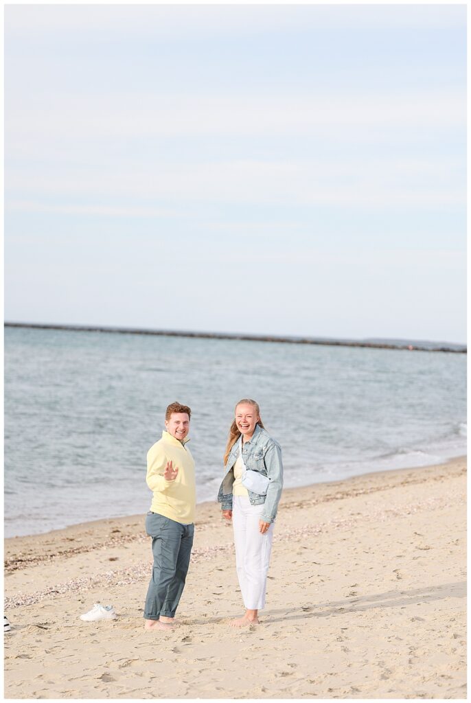 Newly engaged couple waving to Melissa Lacasse their photographer at Steps Beach in Nantucket.