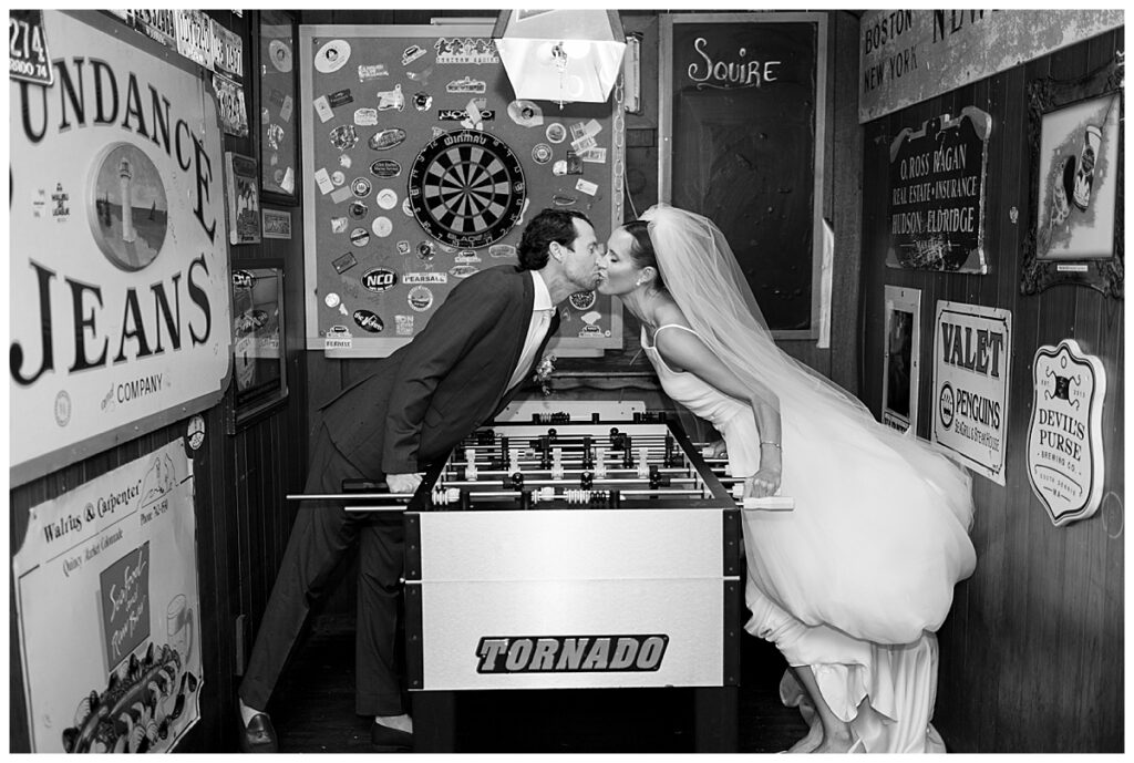 Chatham Squire in Chatham, Ma, Cape Cod. Bride and Groom share a kiss over a pool table during the quick stop on the funk bus.