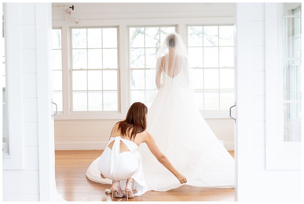 Bride and brides sister fluffing her dress at the Chatham Beach and Tennis Club in Chatham, MA, Cape Cod wedding.