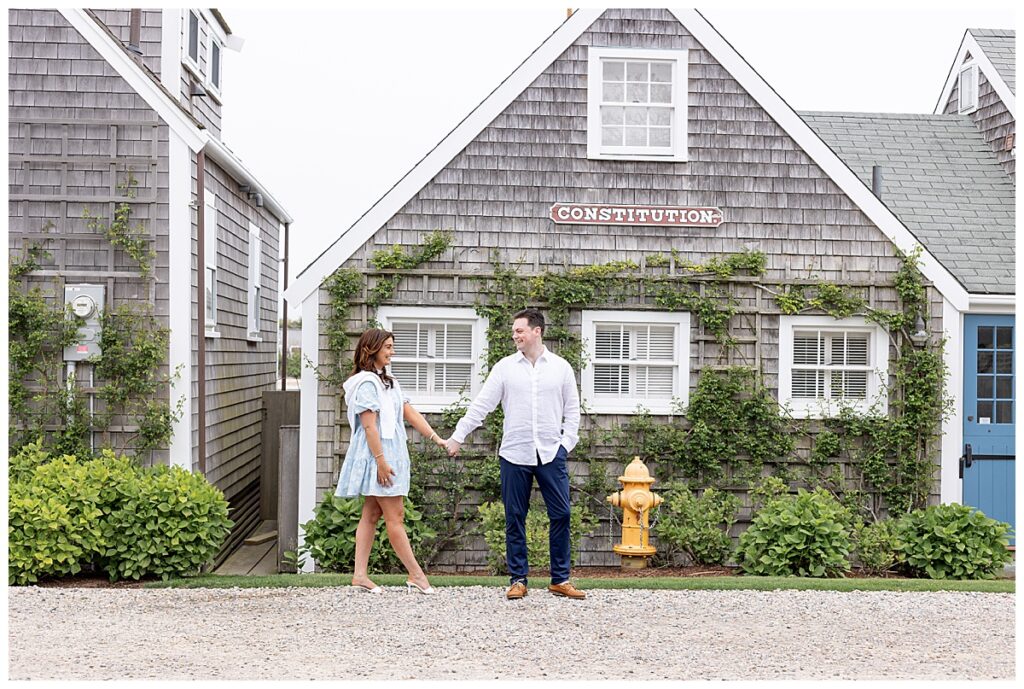 Couple walk along the Old North Wharf in Nantucket during engagement pictures on a spring day in Nantucket.