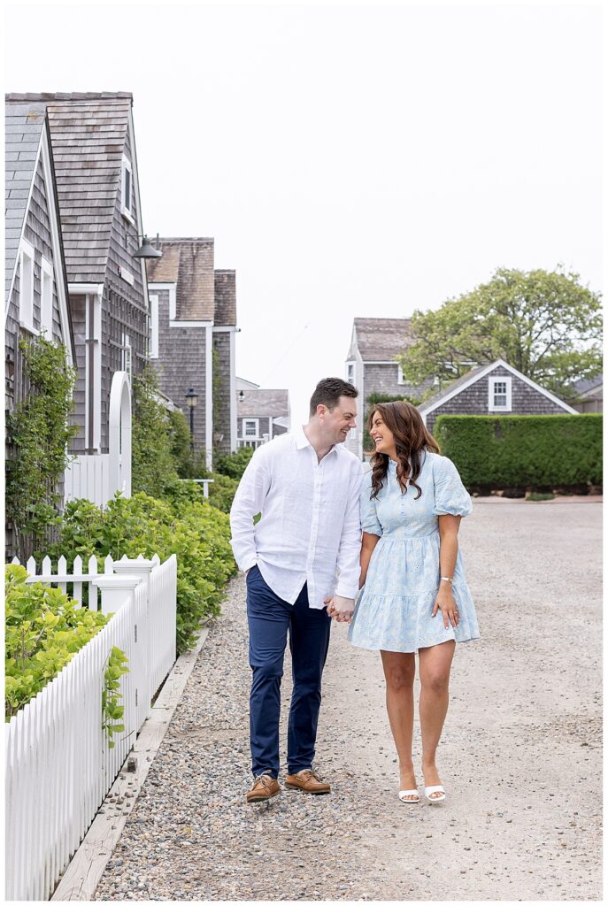 Couple walk along the Old North Wharf and are seen smiling and laughing in Nantucket while having engagement pictures taken.
