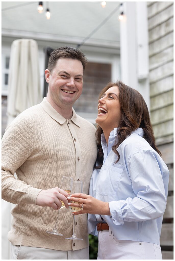 Couple laugh as they take engagement pictures in Nantucket while at Hotel Pippa in the courtyard under string lights.