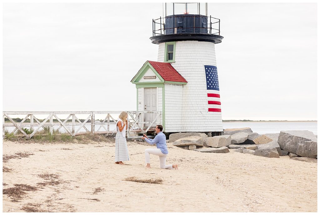 Man gets down on one knee in Nantucket after proposing at Brant Point Lighthouse during his Nantucket Proposal.