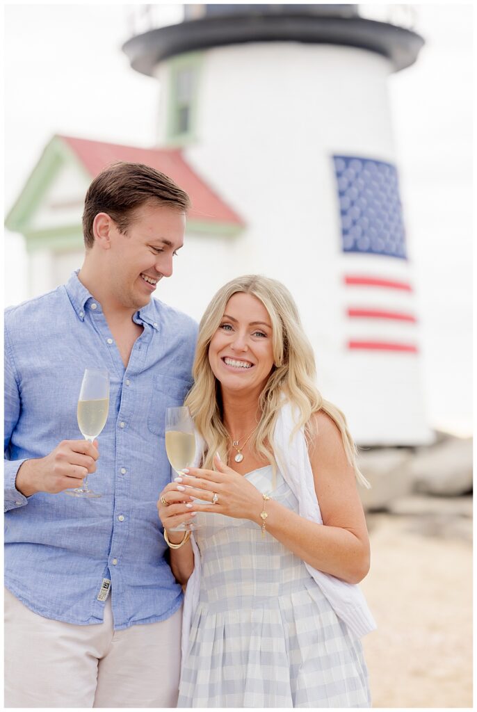 Couple toast to a glass of champagne at Brant Point Lighthouse after a Nantucket Proposal success!