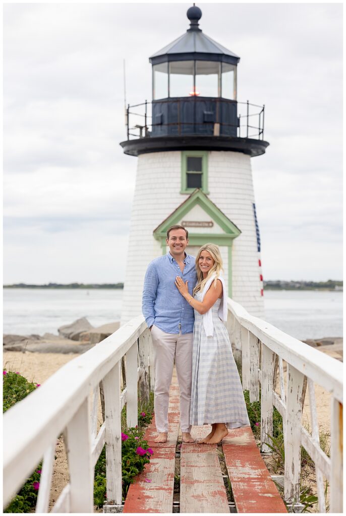 Couple smile at the camera during engagement pictures at Brant Point Lighthouse in Nantucket after his Nantucket Proposal ended up with a yes!