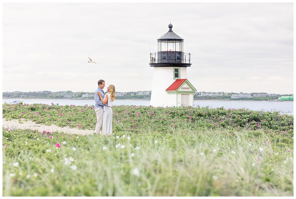 Couple stare lovingly at one another in front of Brant Point Lighthouse in Nantucket after his Nantucket Proposal.