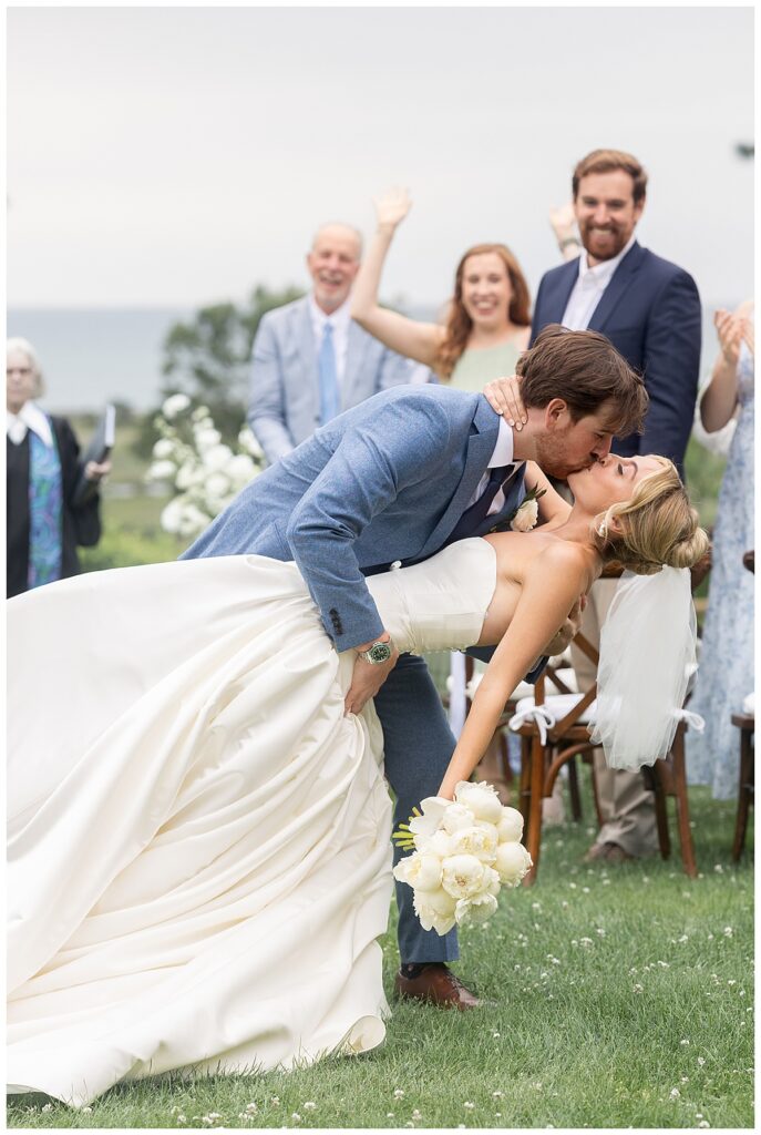 Groom dips bride back and kisses her as they exit the aisle during their wedding ceremony at a Chatham, Cape Cod wedding.