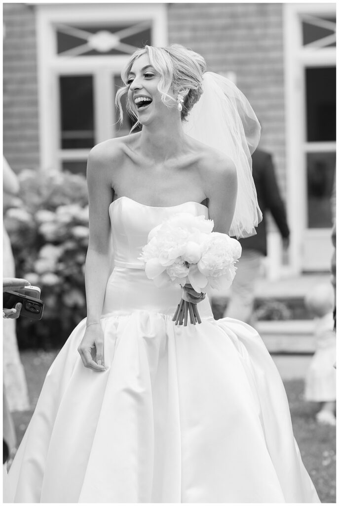 Black and white image of a bride laughing post ceremony at her Chatham, Cape Cod wedding.