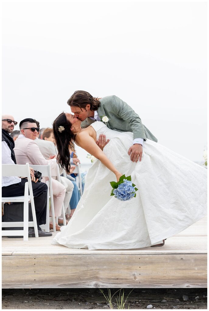 Groom dips bride back and kisses her while walking down the aisle on the Zen Deck at The Wauwinet in Nantucket.