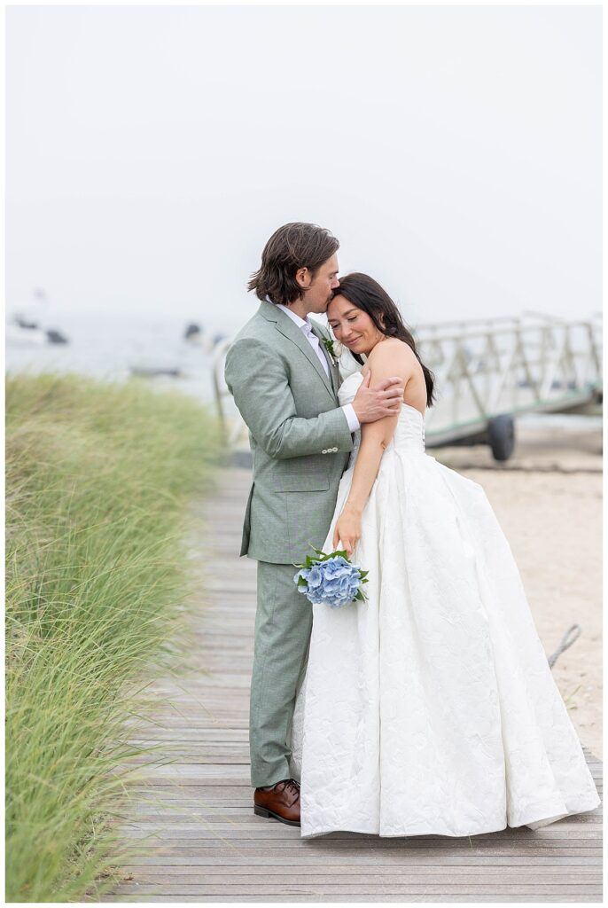 Bride and Groom embrace one another on the boardwalk at The Wauwinet in Nantucket.