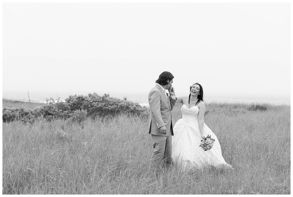 Black and white portrait in the seagrass overlooking the ocean laughing on their wedding day at The Wauwinet in Nantucket.
