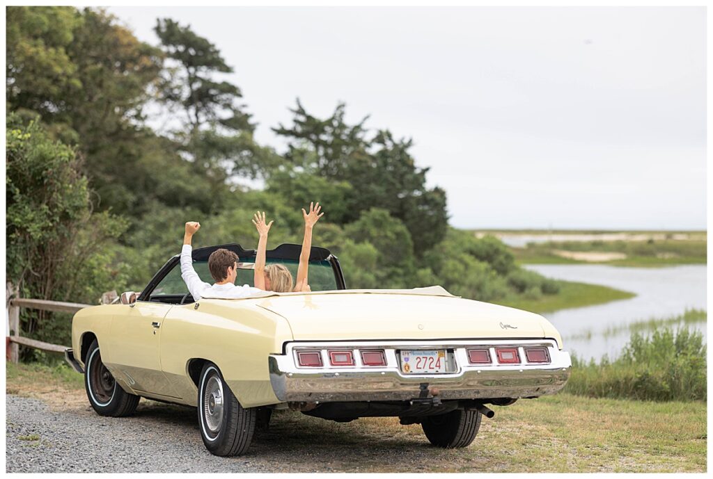 Man and woman sit in vintage pale yellow car after getting engaged in Chatham, Cape Cod, Massachusetts.