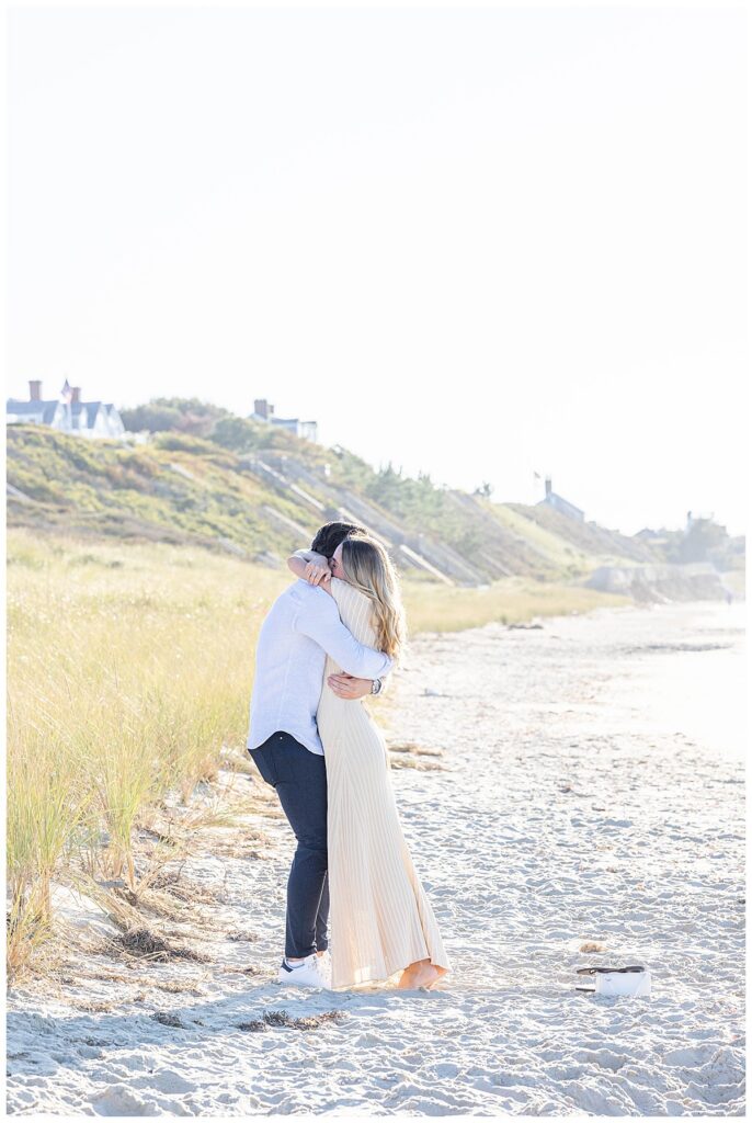 Man and woman stand up crying and laughing while hugging on Steps Beach after mans Nantucket Proposal.