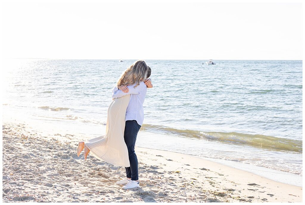 Man spins woman around over Labor Day weekend in excitement after getting engaged at Steps Beach in Nantucket.