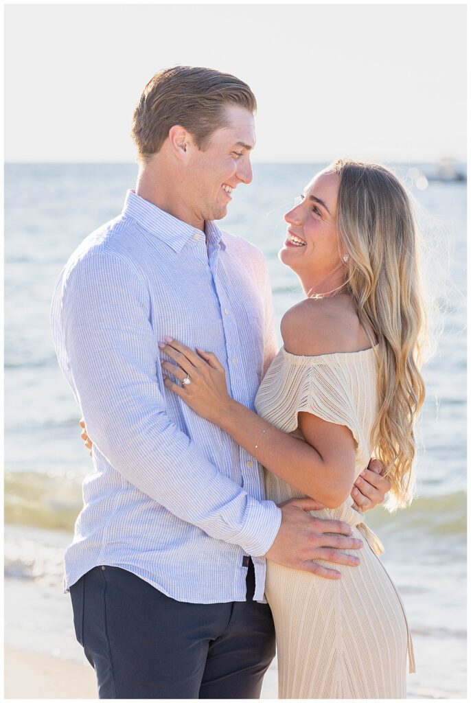 Man and woman smile at one another at Steps Beach after his proposal in Nantucket.