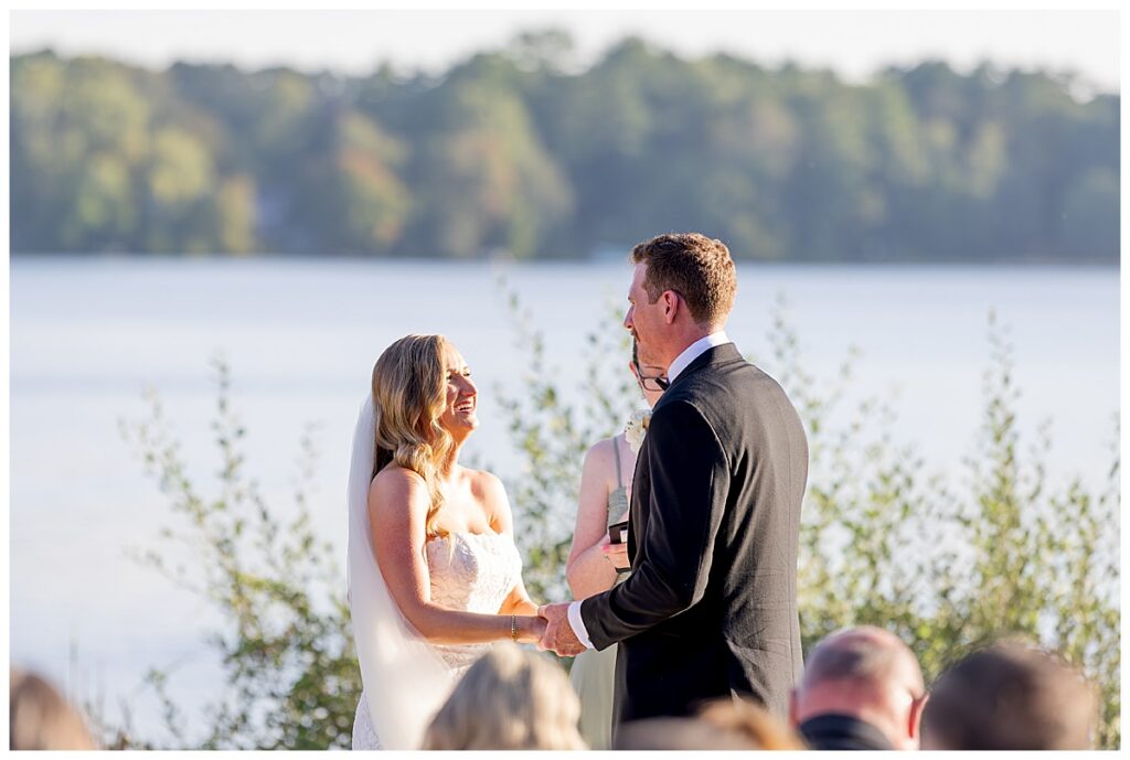 Bride laughs while standing outside during ceremony vows at The Lakehouse, a Sapphire Event Group venue in Halifax, Cape Cod, Massachusetts.