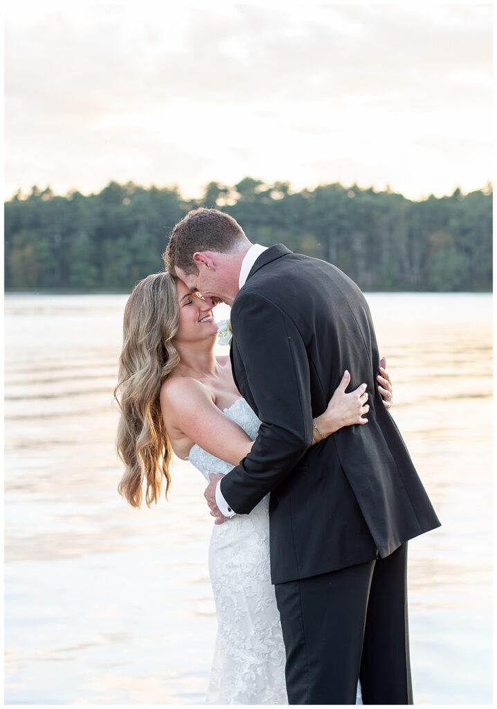 Bride and Groom touch foreheads with eyes closed while he leans her backwards at sunset at The Lakehouse, a Sapphire Event Group venue in Halifax, Cape Cod, Massachusetts.