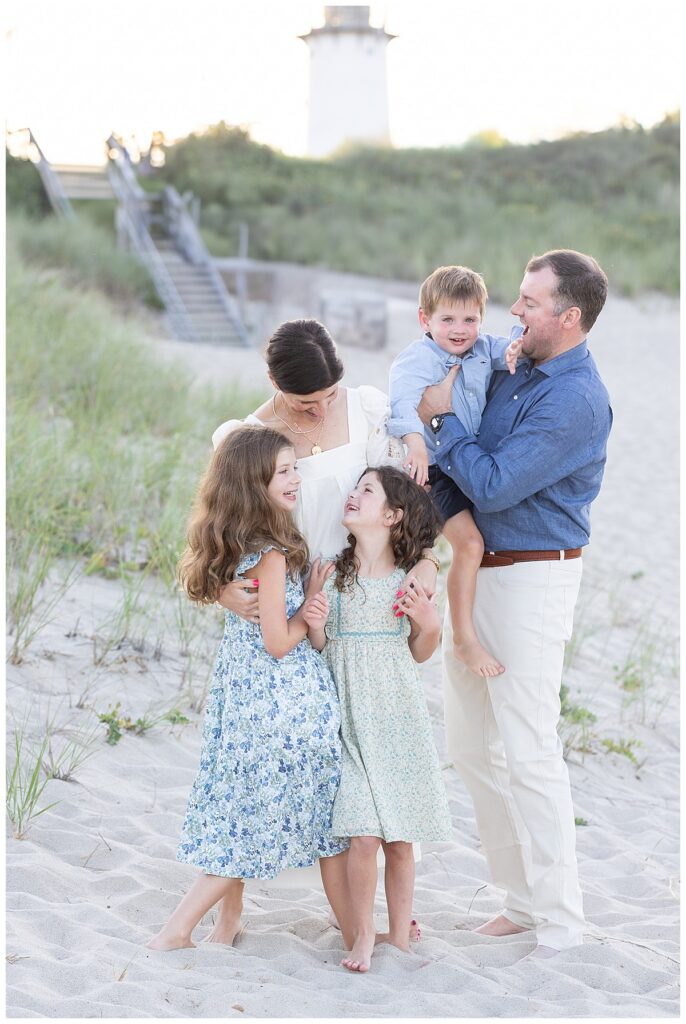 Family smiles at one another in front of Chatham Lighthouse beach at sunset, in Chatham, Cape Cod, Massachusetts.
